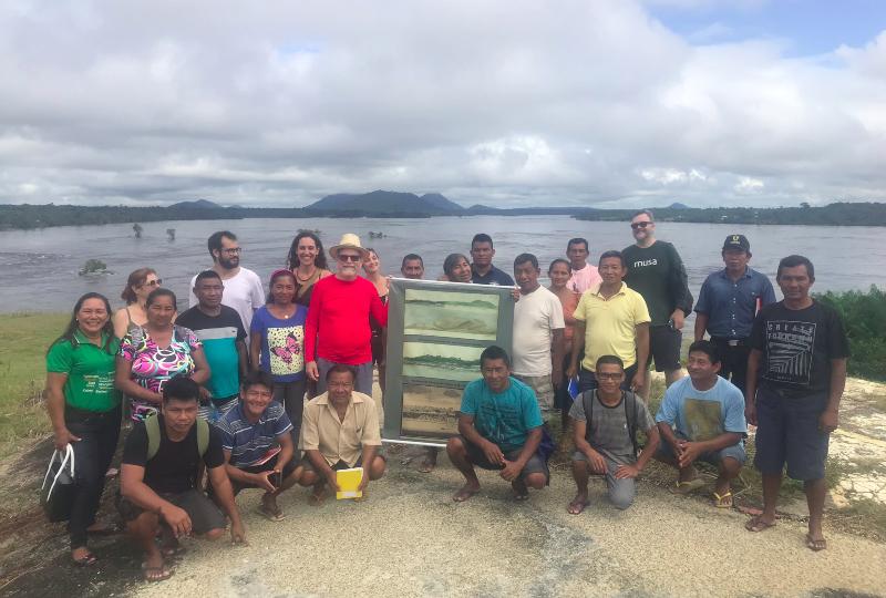 O historiador e antropólogo Márcio Meira (de vermelho), pesquisadores indígenas e não indígenas em visita à Pedra da Fortaleza. Local está em aquarela reproduzida no banner que Meira segura