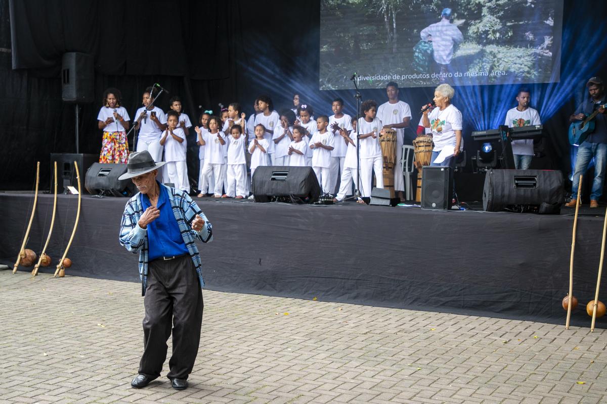 João Santos Rosa, dança enquanto a Dona Elvira Morato, do Quilombo São Pedro, canta a música Tá na Hora da Roça, acompanhada do Grupo Cultural Puxirão Bernardo Furquim