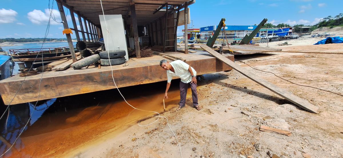 Conhecido como Joaquim 90, vendedor de gelo não está mais encontrando o produto para oferecer aos clientes. Em frente à sua balsa, ele colocou um marcador para verificar o nível da água