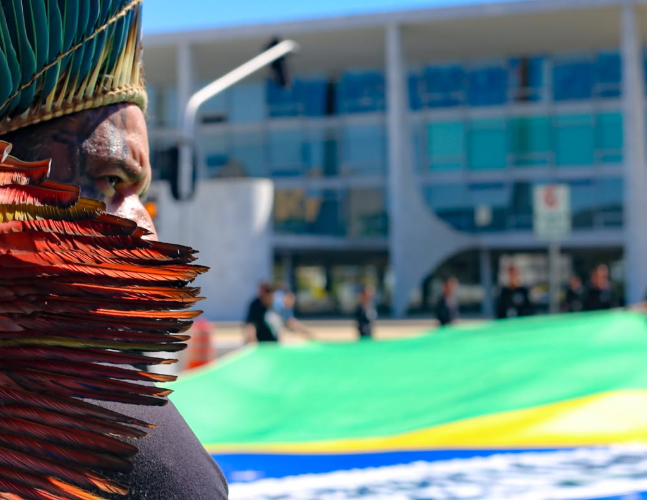 Indígenas abriram uma bandeira do Brasil com a inscrição 'Nosso território, Nossa Vida', na frente do Palácio do Planalto, em Brasília | Scarlett Rocha | Apib